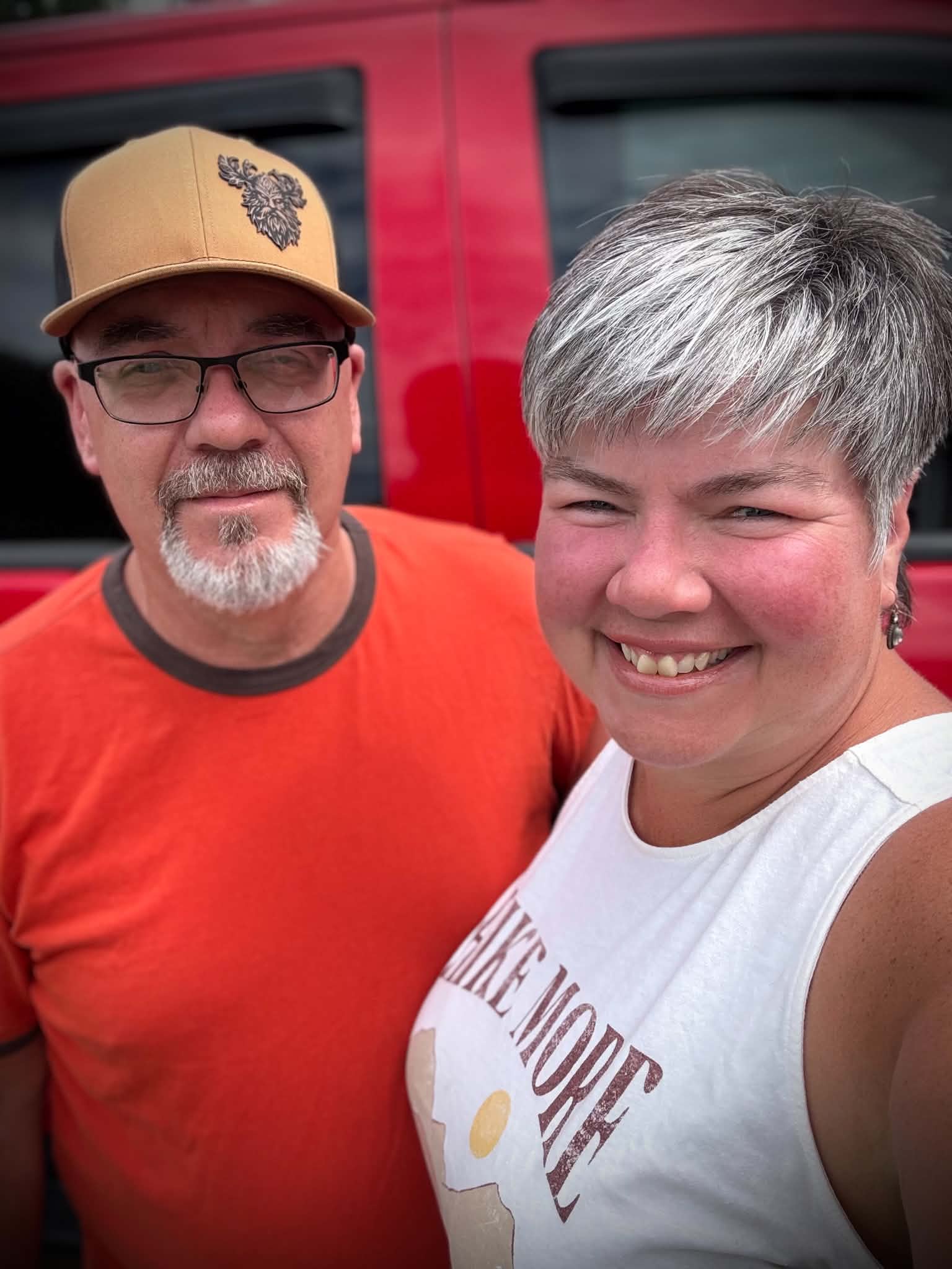 The founders of LESHY Gear standing together in front of a red vehicle